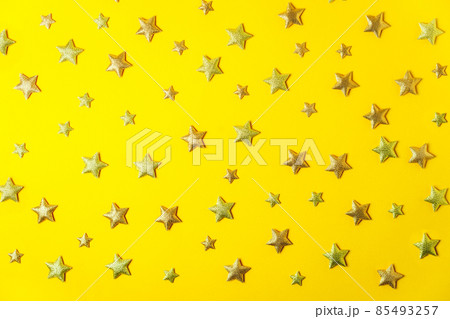 Sparkling and glittering golden stars shape confetti on the bright yellow background. Festive pattern background. Selective focus. Flat Lay, top view. Sparkling and glittering golden stars shape confetti on the bright yellow background. Festive pattern background. Selective focus. Flat Lay, top view. 85493257