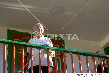 Senior woman at a traditional colorful balcony in the beautiful colonial town of Salento in the region of Quindio in Colombia 85494320