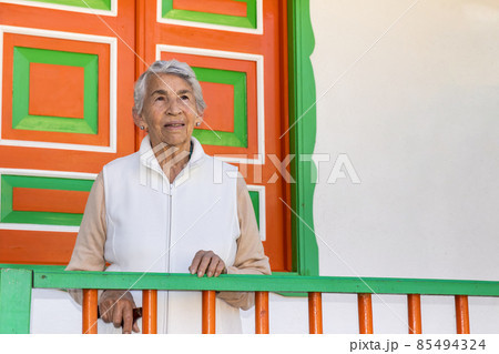 Senior woman at a traditional colorful balcony in the beautiful colonial town of Salento in the region of Quindio in Colombia 85494324