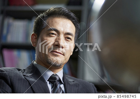 asian corporate executive looking at  a turning tellurian with confidence in office 85498745