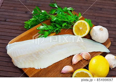 Raw codfish fillet on wooden table with condiments Raw codfish fillet on wooden table with condiments 85499697