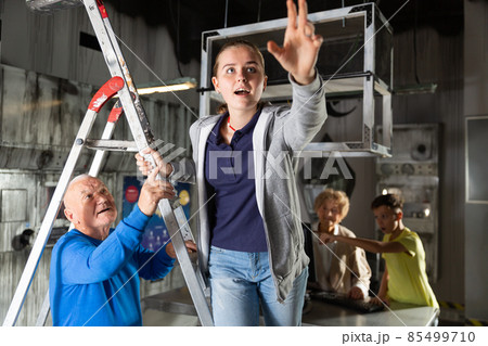 Girl on stepladder in escape room with her family 85499710