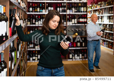 Female customer taking bottle of wine in food shop 85499711