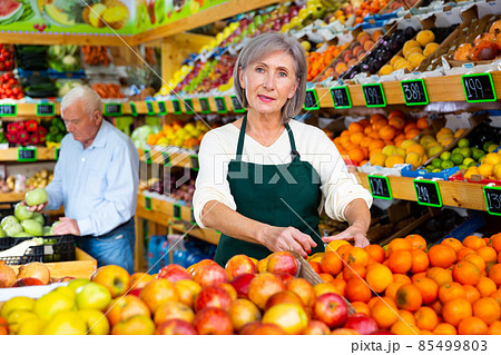 Lady greengrocer worker and old man customer in salesroom 85499803