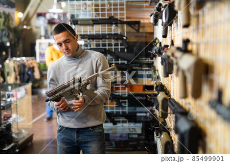 Man chooses semi-automatic pneumatic assault rifle at gun store Man chooses semi-automatic pneumatic assault rifle at gun store 85499901
