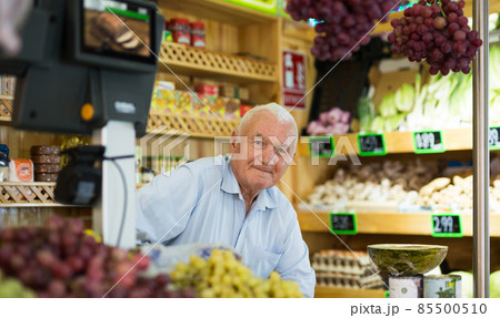 Portrait of a positive male salesperson at the checkout counter at grocery supermarket Portrait of a positive male salesperson at the checkout counter at grocery supermarket 85500510