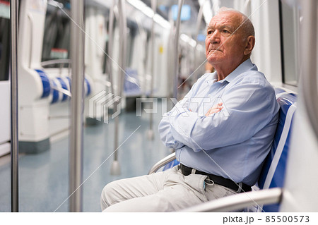 Old man sitting inside subway train 85500573
