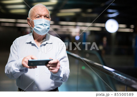 Old man in face mask standing in airport Old man in face mask standing in airport 85500589