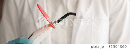 Dentist doctor holds curing light in hand 85504360