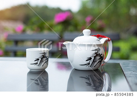 teapot and hot tea to cup on wood table against tea garden view background in the morning, Ban Rak Thai village, Mae Hong Son province, Thailand 85504385