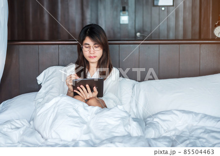 Happy woman using tablet for social media, young female watching movies on computer pad on bed at home. technology, network, online shopping, e commerce, lifestyle and digital communication concept Happy woman using tablet for social media, young female watching movies on computer pad on bed at home. technology, network, online shopping, e commerce, lifestyle and digital communication concept 85504463