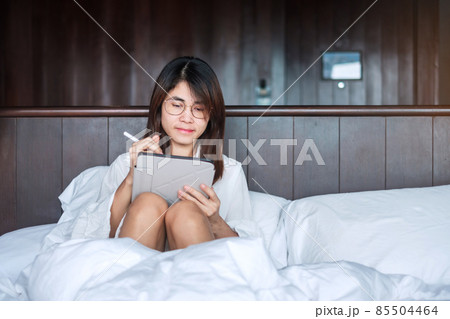 Happy woman using tablet for social media, young female watching movies on computer pad on bed at home. technology, network, online shopping, e commerce, lifestyle and digital communication concept Happy woman using tablet for social media, young female watching movies on computer pad on bed at home. technology, network, online shopping, e commerce, lifestyle and digital communication concept 85504464