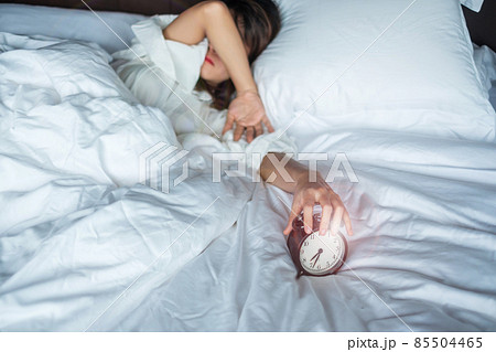 alarm clock and asian woman hand stop time in bed while sleeping, young adult female wake up late in the morning. Relaxing , sleepy, daily routine and have a nice day concepts 85504465