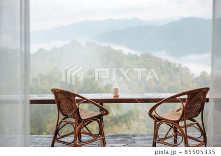 White mug of hot coffee or tea on wooden table in the morning with mountain and nature background White mug of hot coffee or tea on wooden table in the morning with mountain and nature background 85505335