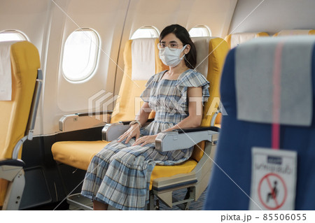 woman wearing protective face mask sitting in airplane or public transportation, protection Coronavirus disease infection, tourist ready to travel. Next Normal, tourism and reopening concept woman wearing protective face mask sitting in airplane or public transportation, protection Coronavirus disease infection, tourist ready to travel. Next Normal, tourism and reopening concept 85506055