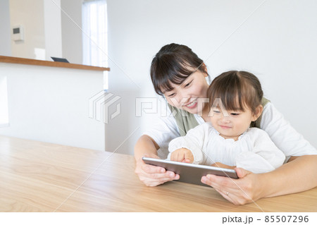 自宅のダイニングでママと一緒にタブレットを見る2歳の女の子 85507296