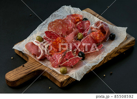 Spanish cold meat assortment. Chorizo, fuet, LOMO, jamon Iberico, olives. Black background. Top view. 85508592