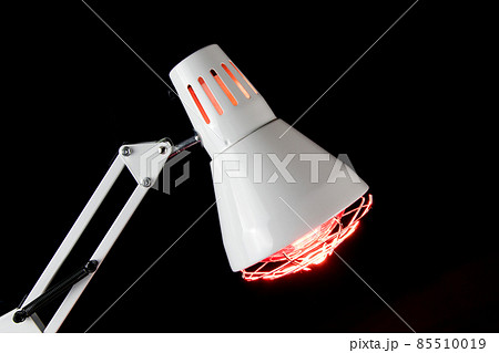 Illuminated Infra Red Health Lamp Closeup on a Black Background 85510019