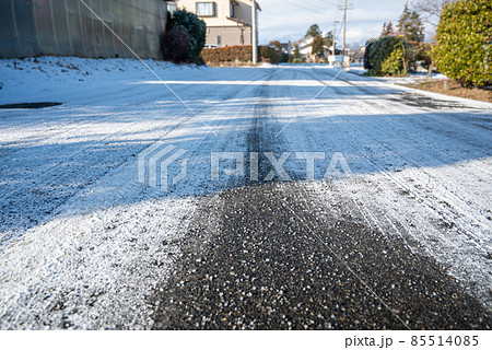 雪の日に塩化カルシウムを撒いた道路 85514085
