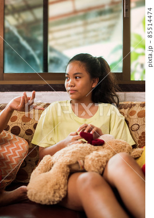 Thai teenager girl sitting on couch with mobile phone and looking to window. 85514474