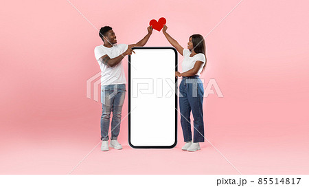 Couple showing white empty smartphone screen holding paper heart 85514817