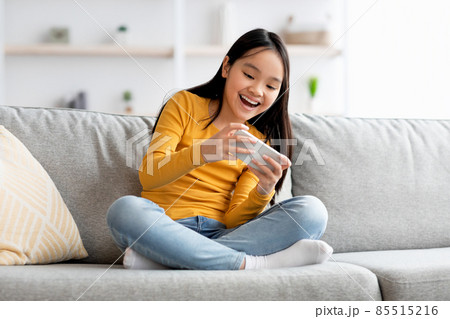 Emotional fmale kid having fun at home, using smartphone Emotional fmale kid having fun at home, using smartphone 85515216