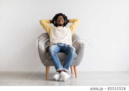 Relax Mode. Young Black Guy Wearing Wireless Headphones Resting In Armchair Relax Mode. Young Black Guy Wearing Wireless Headphones Resting In Armchair 85515528