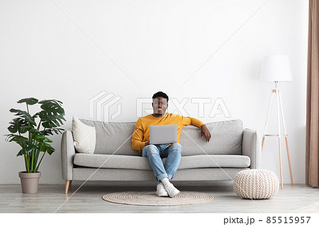 Smiling black guy chilling with laptop at home 85515957