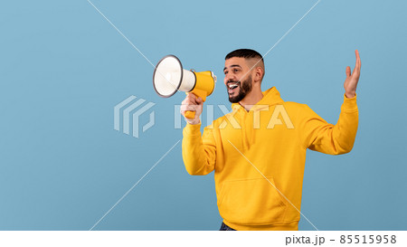 Promo announcement. Happy arab guy with megaphone in hands sharing news or interesting offer, blue background Promo announcement. Happy arab guy with megaphone in hands sharing news or interesting offer, blue background 85515958