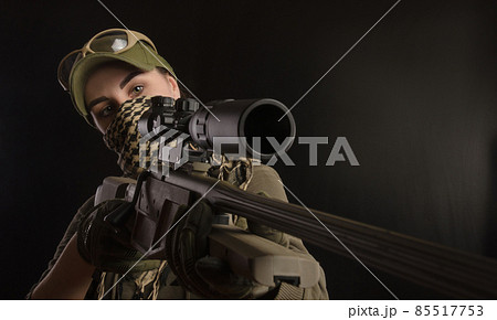 the girl in military special clothes posing with a gun in his hands on a dark background in the haze 85517753