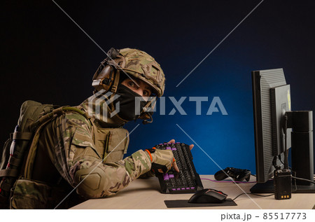 soldier sitting at a computer is conducting a cyber war 85517773