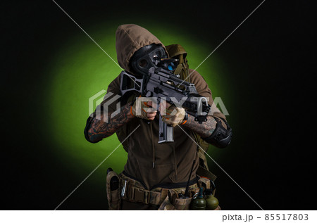 man Stalker with a gun with a telescopic sight and a backpack in a gas mask on a dark background with emotions looking, aiming, watching, sneaking 85517803