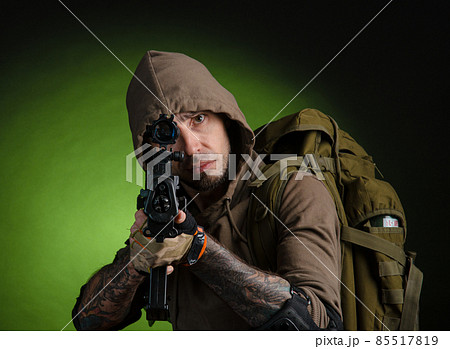 man Stalker with a gun with an optical sight and a backpack on a dark background 85517819