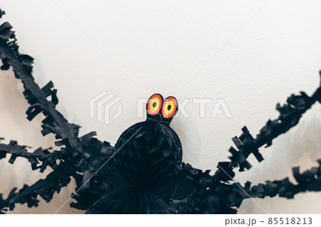 Big yellow eyes of black spider paper decor on white wall. Day of Dead. Halloween decoration. 85518213