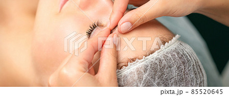 Manual sculpting face massage in the spa. Fingers of beautician make facial massage eyebrow of a young woman in cosmetology clinic, close up. 85520645