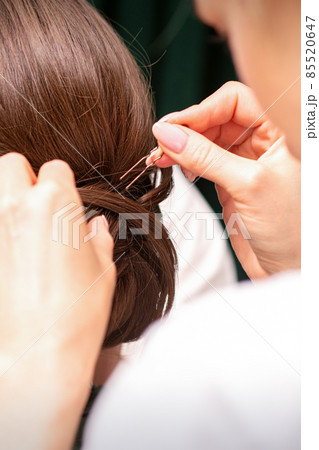 A hairdresser is making the hairstyle of a young brunette woman in a hair salon, close up. 85520647