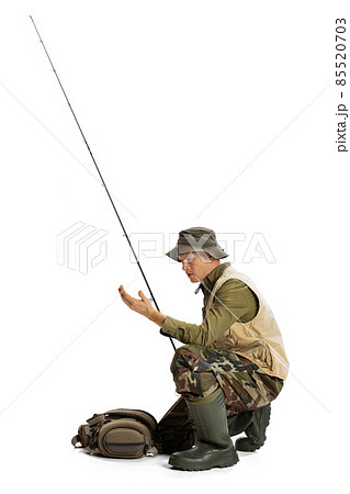 Portrait of young man, professional fisherman with fishing rod, spinning and equipment going to river isolated over white studio background Portrait of young man, professional fisherman with fishing rod, spinning and equipment going to river isolated over white studio background 85520703