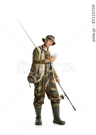Portrait of young man, professional fishman with fishing rod, spinning and equipment going to river isolated over white studio background 85520709