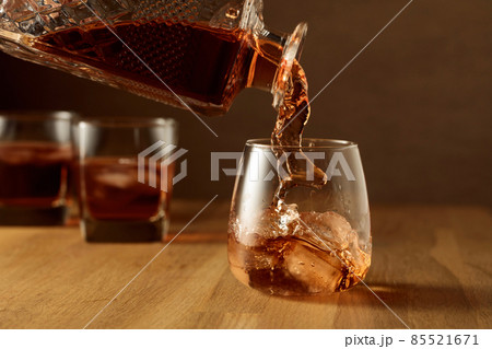 Whiskey is poured into a dammed glass with ice. 85521671