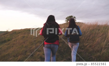 Girls with backpacks climb high up the mountain helping each other on a hiking trip. Women spend the weekend traveling in nature overcoming obstacles. Teamwork. Friends are looking for adventure Girls with backpacks climb high up the mountain helping each other on a hiking trip. Women spend the weekend traveling in nature overcoming obstacles. Teamwork. Friends are looking for adventure 85522381