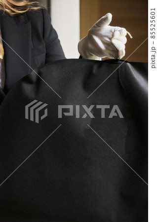 Black garment, suit travel bag. the hands of a hotel worker in white gloves. Black garment, suit travel bag. the hands of a hotel worker in white gloves. 85525601