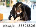 明治神宮で願い事のお札を書いている女性01 85528326