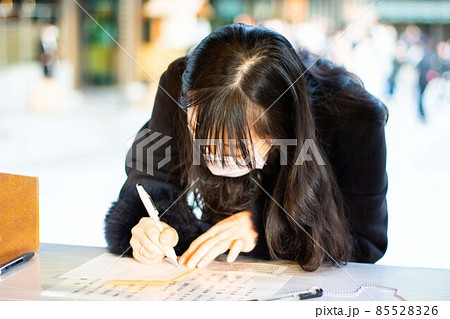 明治神宮で願い事のお札を書いている女性01 85528326