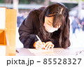 明治神宮で願い事のお札を書いている女性02 85528327