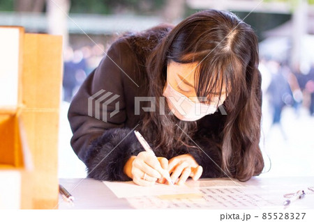 明治神宮で願い事のお札を書いている女性02 85528327