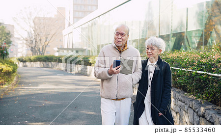 スマホを持って歩くシニアカップル 85533460