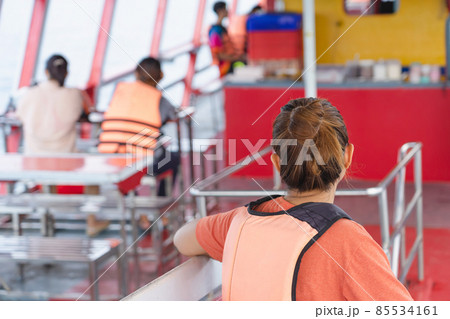 Back view of Asian woman in life vest relaxing on balcony enjoying view from boat of Samui island in the sea. Happy casual female tourists outside on tropical holiday destination.Cruise ship vacation. 85534161