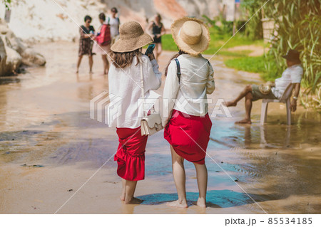 Back view of tourists walk on feet in the Red Stream ( it also named Fairy Stream) with Beautiful scenic landscape with red river, sand dunes and jungle. Tropical oasis scenery in Vietnam. 85534185