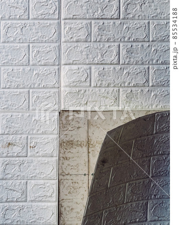 The wallpaper begins to peel off. Old white bricks wallpaper peeled off from the wall inside the room due to moisture or poor quality gluing. Repair and construction services concept. Selective Focus. 85534188