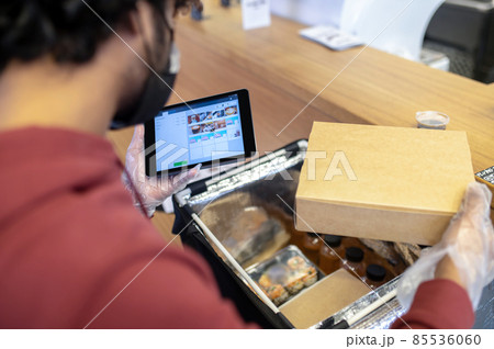 Courrier checking the order for food delivery Courrier checking the order for food delivery 85536060